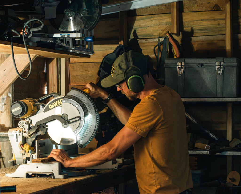 David Woodwork David Yinhar cutting wood with a miter saw in a shop